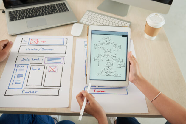 Web designer and Programmierer diskutieren ein Webseiten-Projekt in einem Meeting, um bessere SEO Resultate zu erzielen und die Webseite zu verbessern.